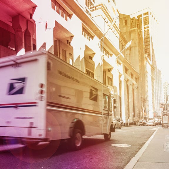 A white truck driving down a city street on a sunny day.